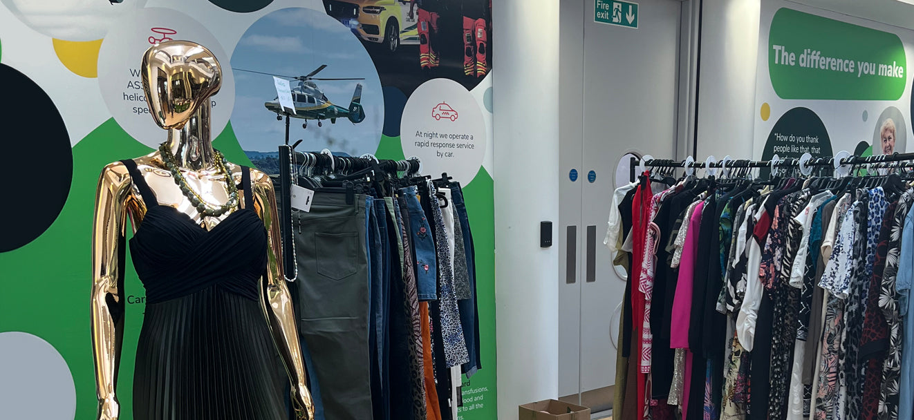 A gold female mannequin, with clothing rails in a pop-up shop