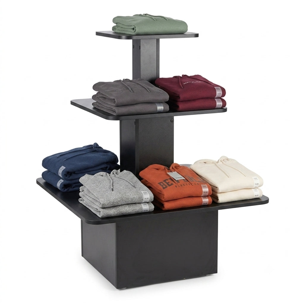 A three-tier black retail clothing display stand holding folded hoodies in green, gray, burgundy, navy, heather gray, rust orange, and cream, set against a plain white background.