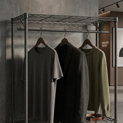 Three garments hanging on a metal clothing rack in a styled interior: a heather gray short-sleeve T-shirt, a black blazer, and an olive green knit sweater. The rack is set against a textured concrete wall with warm ambient lighting.